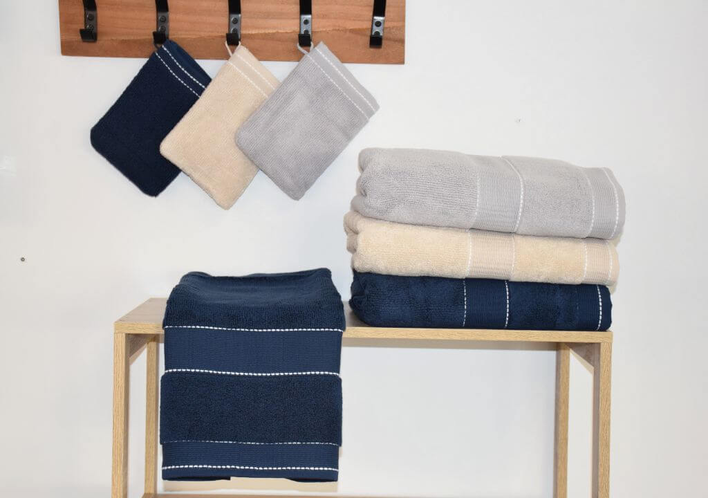 Collection de linge de bain avec des serviette de couleur beige, marine ou gris.